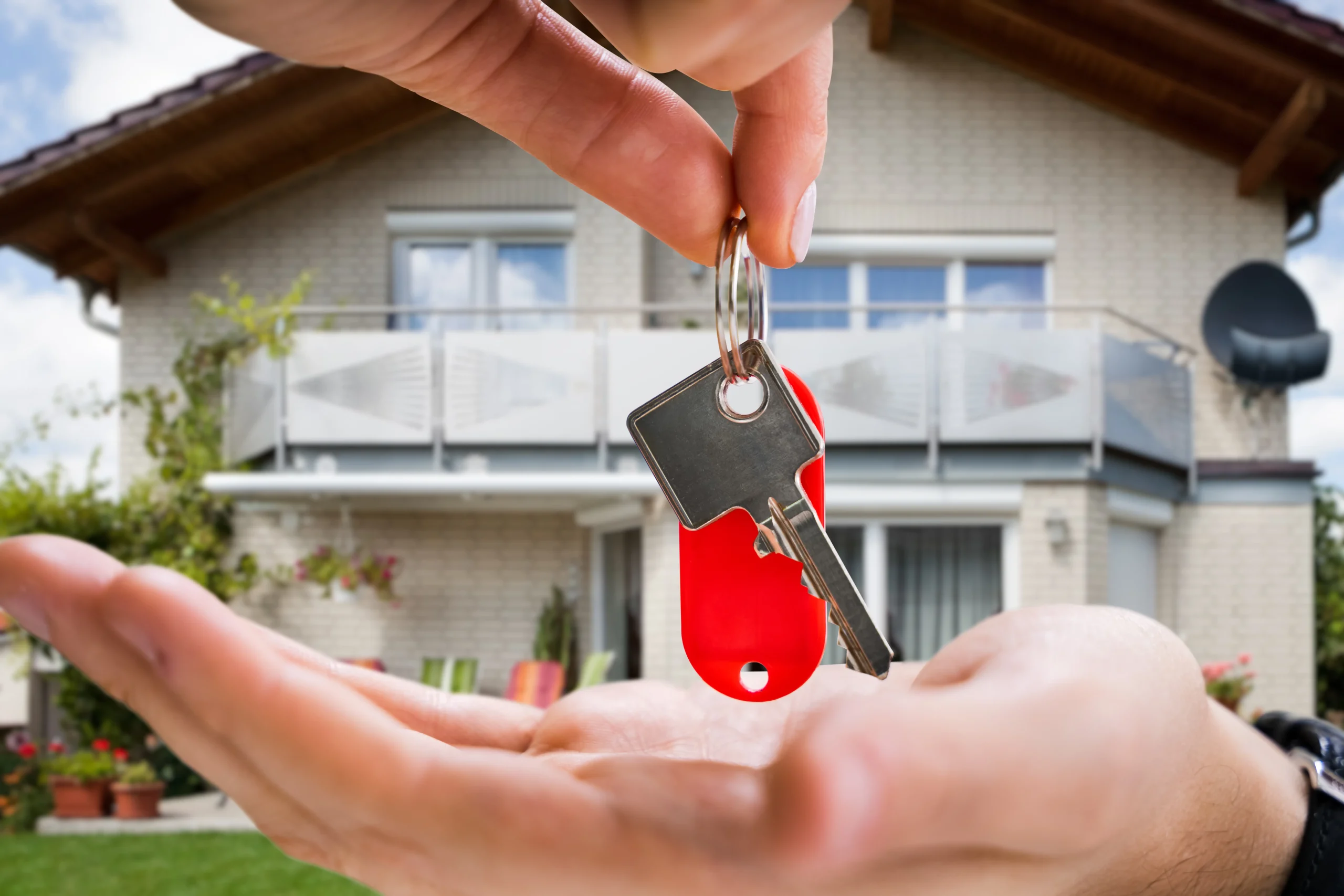 Remise de clés devant une maison individuelle, symbole de l’achat d’une maison construite par un particulier.