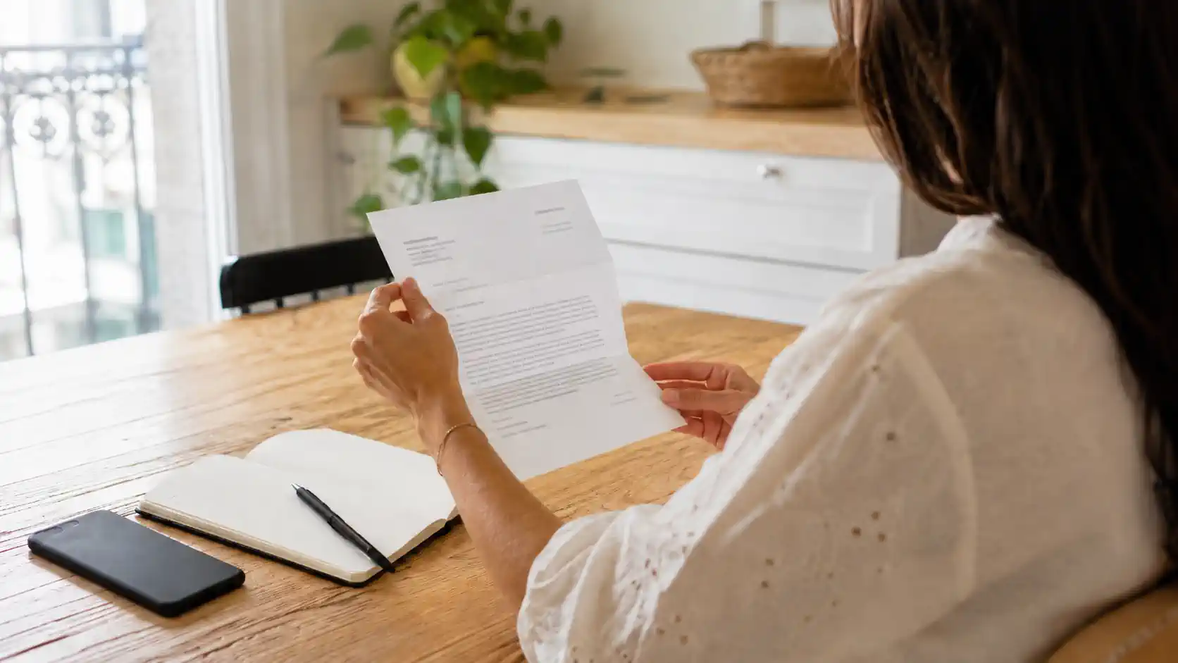 Personne consultant un courrier d’huissier avec un carnet pour noter les démarches