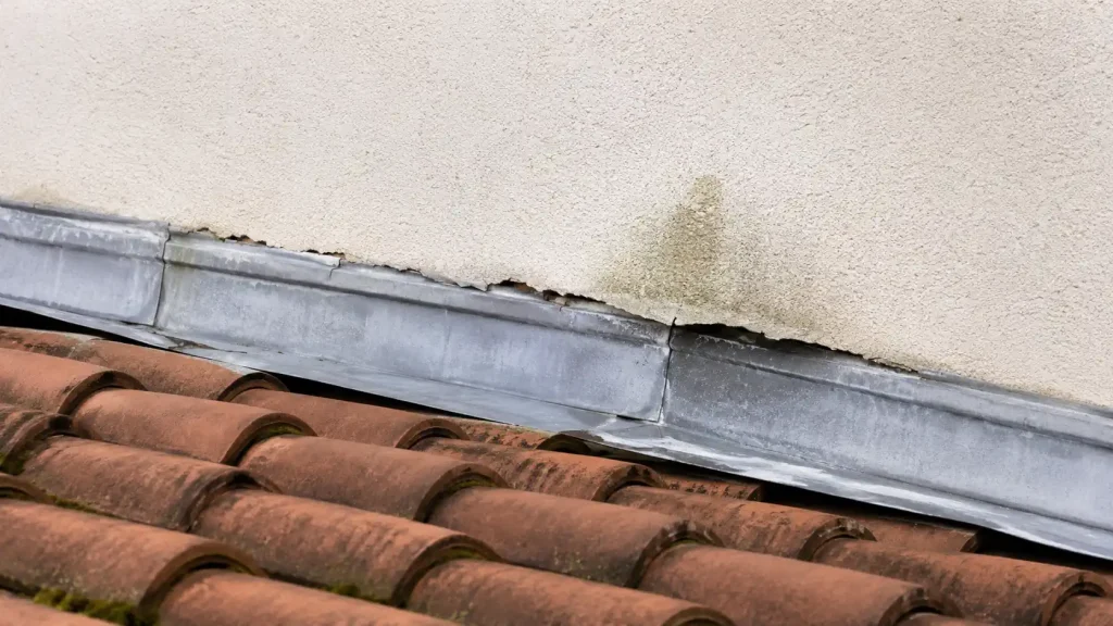 Ancien solin contre mur avec joint fissuré et trace d’humidité sur l’enduit